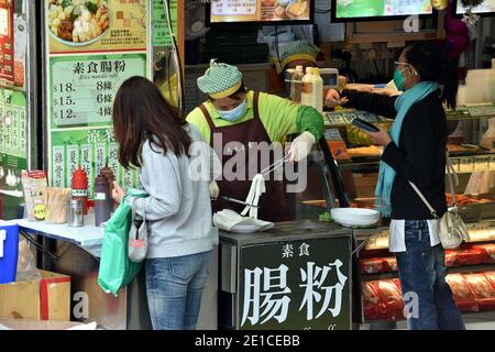 Hongkong, China. Januar 2021. Menschen mit Gesichtsmasken kaufen an einem Stand in Hongkong, Südchina, Essen, 6. Januar 2021. Hongkongs Zentrum für Gesundheitsschutz meldete am Mittwoch 25 weitere bestätigte Fälle von COVID-19, ein neuer Tiefstand seit Ende November, der sich auf 9,074 annahm. Kredit: Lo Ping Fai/Xinhua/Alamy Live Nachrichten Stockfoto