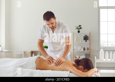 Die junge Frau liegt während einer Wellness-Körpermassage in einem Massagesalon auf einem Massageliegen. Stockfoto