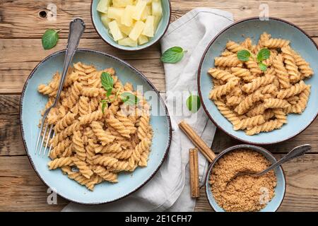 Einfache Fusilli-Pasta mit süß gebratenem Grieß und Zimt, serviert mit Ananasstücken Stockfoto