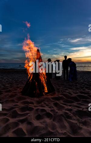 Nicht erkennbare Menschen feiern Sommersonnenwende mit Lagerfeuer am Strand Stockfoto