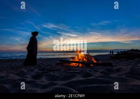 Nicht erkennbare Menschen feiern Sommersonnenwende mit Lagerfeuer am Strand Stockfoto