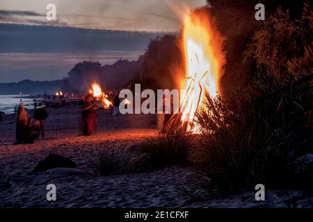 Nicht erkennbare Menschen feiern Sommersonnenwende mit Lagerfeuer am Strand Stockfoto