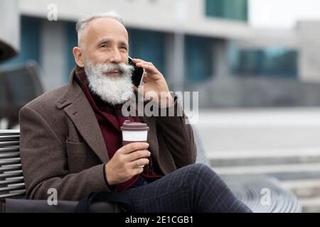 Gutaussehender älterer Mann mit Kaffee zu gehen mit Geschäftsanruf Stockfoto
