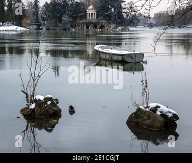 Schneebedecktes Boot im See und Love Temple im Hintergrund. Daumesnil-See (Wald von Vincennes, Paris, Frankreich). Stockfoto