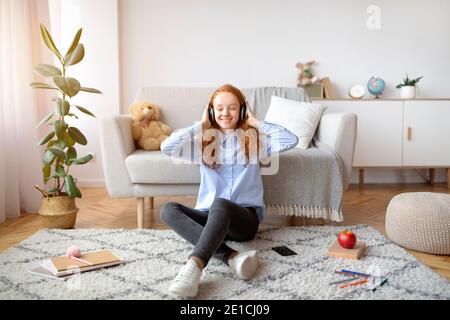 Teenager-Mädchen auf dem Teppich sitzen, Musik hören Stockfoto