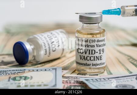Covid-19 Coronavirus-Impfstoff mit hypodermischer Spritzennadel auf Stapel sitzend Von Bargeld, um die Zahlung vorschlagen, um die Impfung zu erhalten Stockfoto