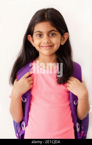 Porträt eines schönen kleinen indischen Mädchen mit lila Rucksack warten auf die Rückkehr in die Schule während der Covid-19 Pandemie Ausbruch. Stockfoto