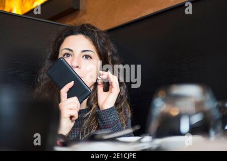 Schöne junge Geschäftsfrau sitzen und sprechen auf Handy Im Restaurant Stockfoto