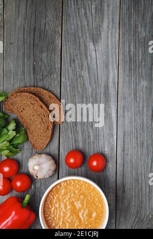Frische Tomatensuppe mit Gemüse auf einem Holztisch. Von oben betrachtet. Leeres Leerzeichen für Text Stockfoto