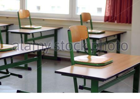 Ein Satz von Stühlen auf der Schule deaskiert in einem verlassenen Klassenzimmer als die Corona-Krise weiter. Stockfoto