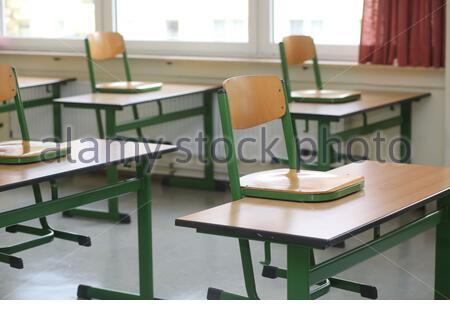 Ein Satz von Stühlen auf der Schule deaskiert in einem verlassenen Klassenzimmer als die Corona-Krise weiter. Stockfoto