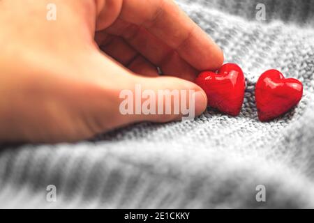 Valentinstag Komposition, rote Herzen und Hand des Jungen, Mann abholen Herz, Paar Liebe Konzept Foto Stockfoto