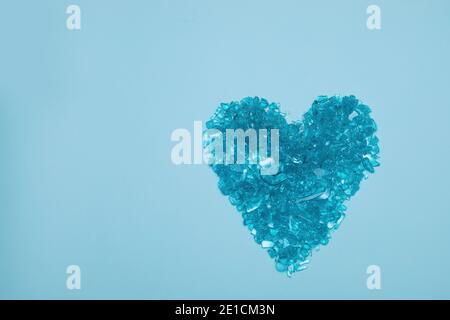 Herz aus gebrochenem Glas auf blauem Hintergrund. Konzept des gebrochenen Herzens aus Scherben. Valentinstag Stockfoto