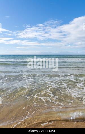 Vertikale Ansicht des klaren tropischen Ozeans Wasser mit Wellen an Ein goldener Sandstrand Stockfoto