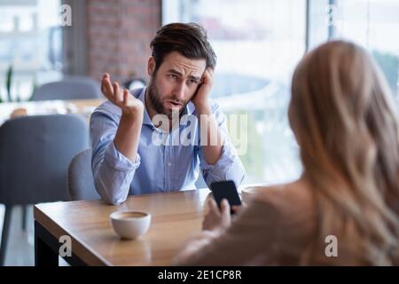 Irritiert Millennial Kerl und seine Freundin stecken in Smartphone an Café Stockfoto