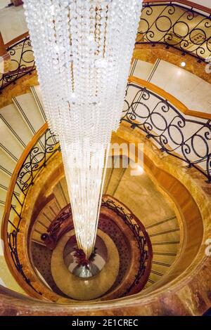 Dreistöckiger Kronleuchter aus tropfendem Kristall in einer Wendeltreppe Stockfoto