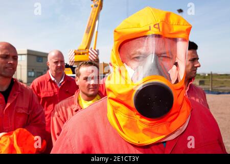 Arbeiter in der Offshore-Industrie üben im Rahmen eines Industrieschulungskurses aus einer Rauchkammer zu fliehen, dass alle Offshore-Mitarbeiter verpflichtet sind Stockfoto