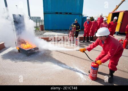 Arbeiter in der Offshore-Industrie üben die Brandbekämpfung mit einem Pulverlöscher im Rahmen einer Branchenschulung, die alle Offshore-Mitarbeiter a Stockfoto