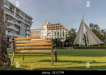 Holzbänke auf Grasboden in einem schattigen Bereich des Parks in Condominium. Sitz- und Relaxbereich. Selektiver Fokus. Stockfoto