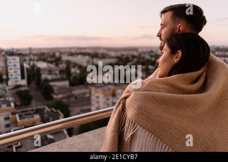 Nahaufnahme Porträt, Mann und Frau lächeln einander bei Sonnenuntergang mit Stadt im Hintergrund. Romantische Momente im intimen Kreis Stockfoto