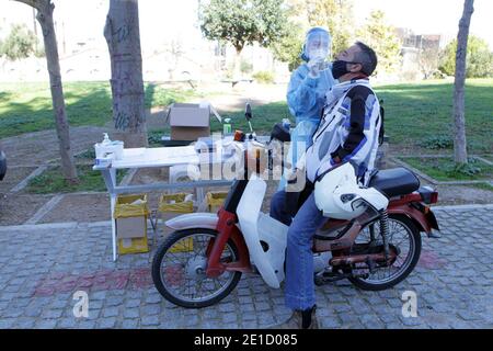 Medizinisches Personal der National Health Organization (EODY) führt einen COVID-19 Schnelltest an einem Motorradfahrer auf einem Drive-Through Testgelände im Zentrum von Athen durch. Stockfoto