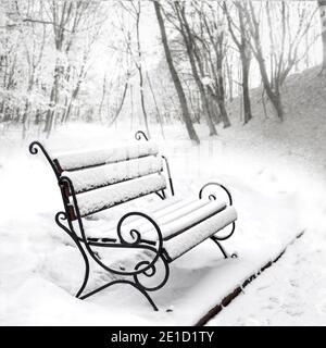 Der Winter ist gekommen. Eine leerstehende Bank, die in einem Winterpark mit Schnee bedeckt ist. Kopierbereich Stockfoto