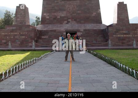 Peter Martin Rhind, der den Äquator in Ecuador vor dem Äquatordenkmal in Quito überspannt. Stockfoto