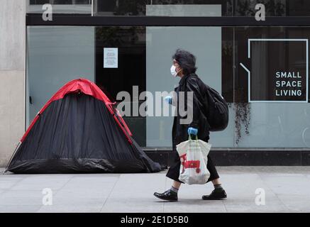 Aktenfoto vom 15/05/20 einer Frau, die an einem Zelt einer Obdachlosen vorbeigeht, das vor einem Möbelgeschäft in der Tottenham Court Road, London, errichtet wurde. Die Regierung wird aufgefordert, zu erläutern, wie sie Obdachlose während der Sperrung schützen wird, und fordert sie auf, ihre Anweisung an die Räte zu wiederholen, um rasch alle von der Straße zu bringen. Stockfoto