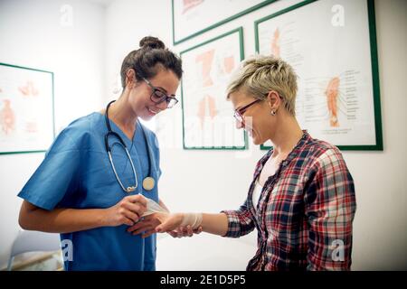 Professionelle tragen medizinische Krankenschwester legte einen Verband auf eine junge Mädchen verletzt Hand. Stockfoto