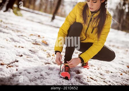 Nahaufnahme einer Frau, die Schnürsenkel bindet. Training in der Natur im Winter. Stockfoto