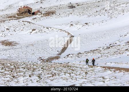 Zwei Bergsteiger, die im Winter und mit Schnee an der Hütte Poqueira am Südhang der Sierra Nevada ankommen. Stockfoto