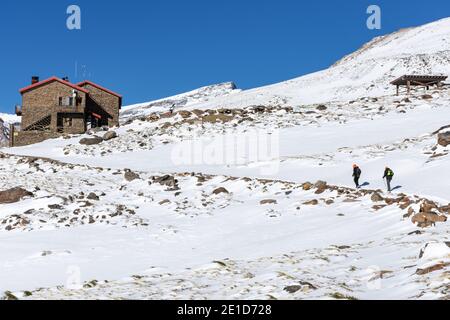 Zwei Bergsteiger, die im Winter und mit Schnee an der Hütte Poqueira am Südhang der Sierra Nevada ankommen. Stockfoto