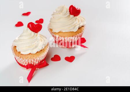 Zwei Valentinen Cupcakes mit Herzen geformt Karamell Süßigkeiten gebunden rot Farbbänder Stockfoto