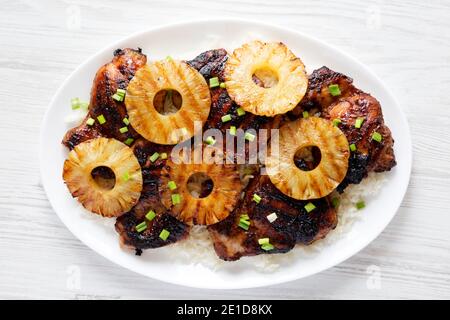 Hausgemachte Hawaiian Huli Huli Huhn auf einem weißen Teller auf einem weißen Holztisch, Draufsicht. Flachlage, über Kopf, von oben. Stockfoto