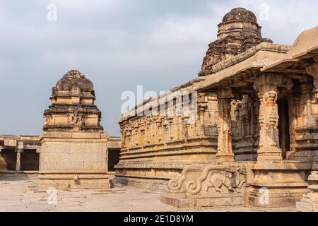 Hampi, Karnataka, Indien - 5. November 2013: Sri Krishna Tempel in Ruinen. Gelb-brauner Schrein an der Seite der Fassade mit Stufen zum Betreten, geformte Säulen, Stockfoto