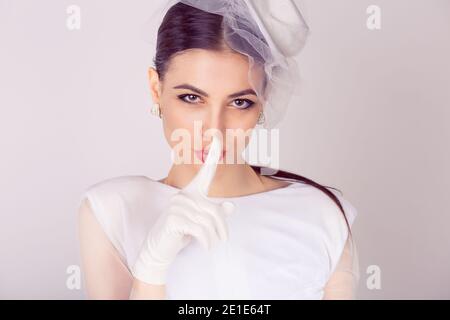 Braut Retro gestylt shh Frau weit Augen bitten um Ruhe Geheimhaltung mit Finger auf den Lippen Stille Hand Geste weiß Stockfoto