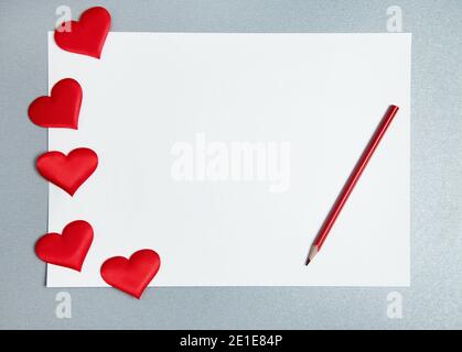 Flach legen mit weißem Blatt Papier, roten Bleistift und breiten Herzen auf einem grauen Hintergrund. St. Valentines Day Konzept. Stockfoto