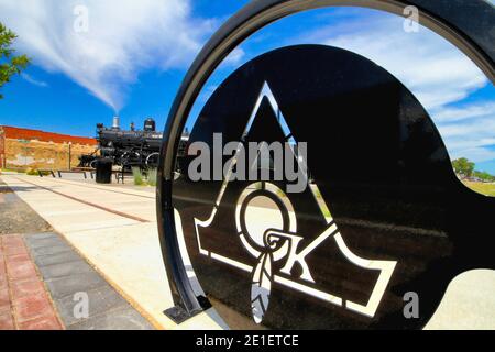 Der historische Mercy Train und Depot Park im Hintergrund, hinter einer Nahaufnahme eines Metallschilds 'A OK' in der Innenstadt von Ardmore. Stockfoto