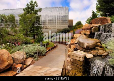 Die Crystal Bridge, ein einzigartiger runder, mit Glas umschlossener tropischer Wintergarten in den Myriad Gardens der Innenstadt von Oklahoma City mit Wasserfall und Gehweg. Stockfoto