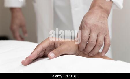 Ein Arzt nimmt den Puls eines Patienten am Handgelenk Stockfoto