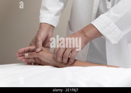 Ein Arzt nimmt den Puls eines Patienten am Handgelenk Stockfoto