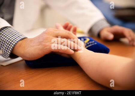 Ein Arzt nimmt den Puls eines Patienten am Handgelenk Stockfoto