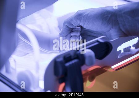 Eine Krankenschwester hält den Fuß eines Neugeborenen in einem Inkubator Stockfoto