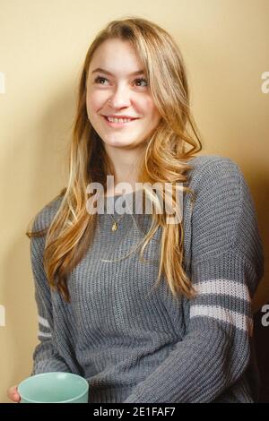 Eine junge Frau mit Nasenring lehnt sich an die Wand Innen lächelnd Stockfoto