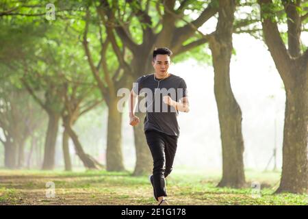 Asiatische junge Mann läuft in den Wald auf neblig an Morgen Stockfoto