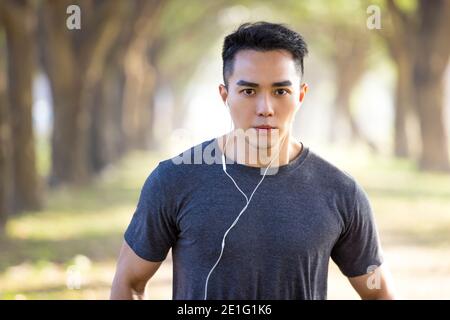 Schöner asiatischer junger Mann, der morgens im Park trainiert Stockfoto