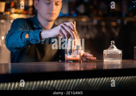 Der Barkeeper bereitet einen traditionellen altmodischen Cocktail mit Whiskey und Orange zu Stockfoto