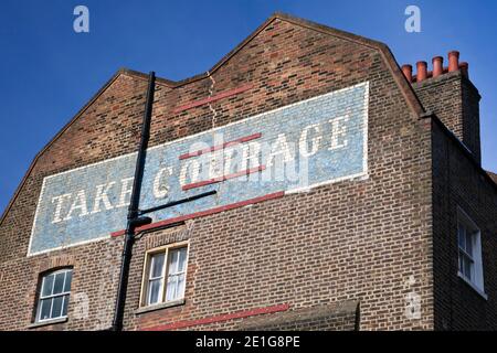 Wandgemälde mit dem Slogan "Take Courage" auf einem Ende des um 1807 für ältere Mitarbeiter der Anchor Brauerei, Borough Mar gebauten Ziegelhauses Stockfoto