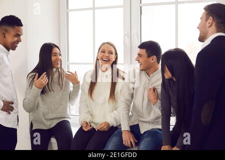 Gruppe von glücklichen jungen Kollegen, Studenten oder Freunden, die über lustige Sachen reden und lachen Stockfoto