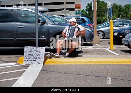 Ein versierter Akkordeonspieler auf dem Parkplatz, der für einen Beitrag zu seinen Familienfinanzen spielt. St. Paul Minnesota, USA Stockfoto
